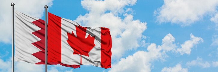 Naklejka premium Bahrain and Canada flag waving in the wind against white cloudy blue sky together. Diplomacy concept, international relations.