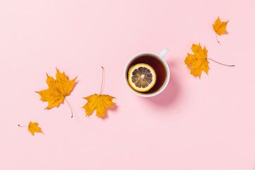 Cozy autumn composition. Tea cup with slice of lemon and maple leaves.