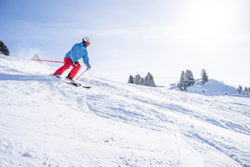 Fototapeta na wymiar Athletic man in helmet and mask skiing on snowy slope .