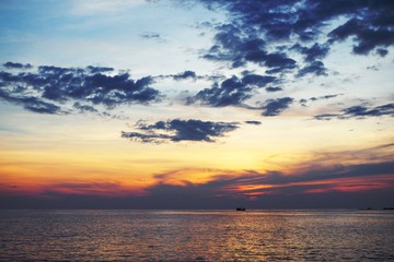 Sunset over sea with reflection in water, majestic clouds in the sky.