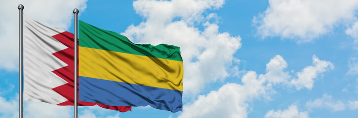 Bahrain and Gabon flag waving in the wind against white cloudy blue sky together. Diplomacy concept, international relations.