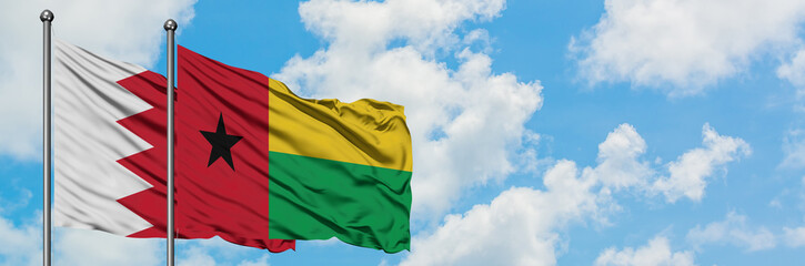 Bahrain and Guinea Bissau flag waving in the wind against white cloudy blue sky together. Diplomacy concept, international relations.