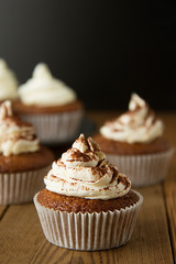 Chocolate cupcakes with whipped cream on rustic wooden table. Homemade dessert.