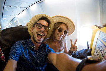Crazy and happy couple take selfie on the airplane during flight. Concept about travel, lifestyle...