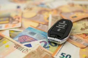 Electronic key chain of a vehicle on bed of fifty and twenty euro bills