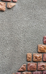 The stone wall with a concrete coat in the form of splashes, drops, rough. upper left and lower right corners with decorative stone.