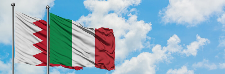 Obraz premium Bahrain and Italy flag waving in the wind against white cloudy blue sky together. Diplomacy concept, international relations.