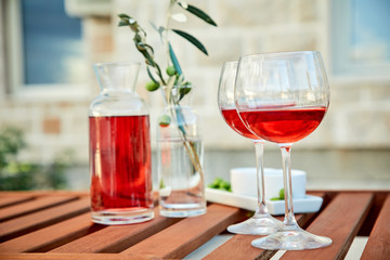 two glasses of rose wine with  olives against blue water on a pier..