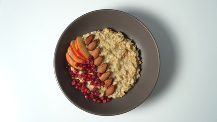 Oatmeal, apples, almonds and lingonberries on a plate. Healthy vegetarian breakfast.