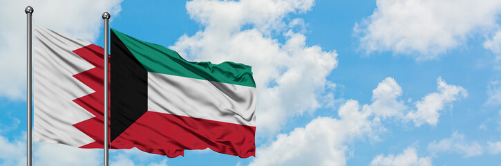 Bahrain and Kuwait flag waving in the wind against white cloudy blue sky together. Diplomacy concept, international relations.