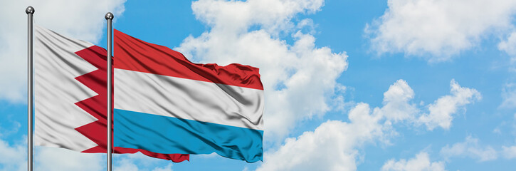 Fototapeta na wymiar Bahrain and Luxembourg flag waving in the wind against white cloudy blue sky together. Diplomacy concept, international relations.