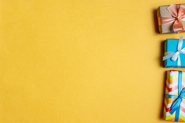 Colorful gift boxes on a yellow background close up. The concept of preparing for the holidays New Year and Christmas.