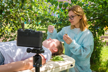Cometologist massage therapist takes care of the skin of a girl on the nature with natural cosmetics and records training on camera, natural cosmetics, blogger, online training, freelance