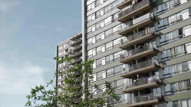 Slow motion gimbal shot of two apartment blocks in front of a small tree
