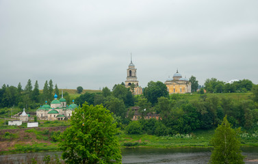 A dilapidated monastery on the river Bank against a dark cloudy sky.