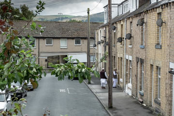  Detailed view of an old-style terraced street showing two adults leaving a house. The narrow street has parking issues in peak periods.