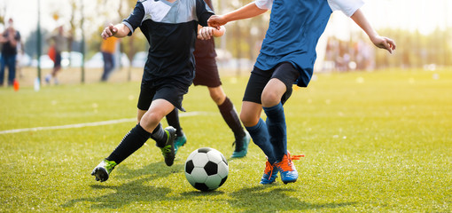 Two soccer players running and kicking a soccer ball. Legs of two young football players on a match. European football youth player legs in action - obrazy, fototapety, plakaty
