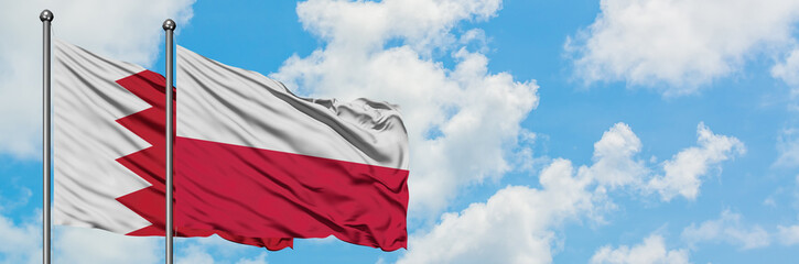 Bahrain and Poland flag waving in the wind against white cloudy blue sky together. Diplomacy concept, international relations.