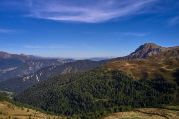 Aerial view of the Alps surrounded by meadows, forests and mountains. Flying on drone.