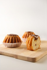 Three freshly baked sweet rum cakes with a cut on the wooden board with copy space, selective focus, vertical image