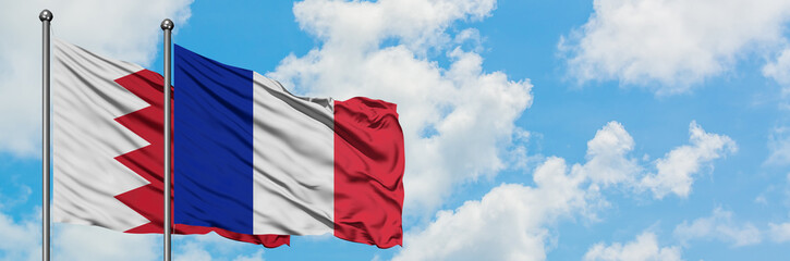 Fototapeta premium Bahrain and Reunion flag waving in the wind against white cloudy blue sky together. Diplomacy concept, international relations.