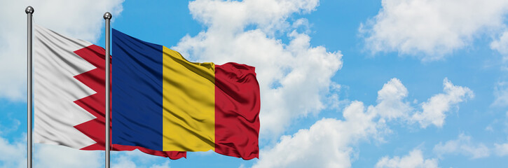 Obraz premium Bahrain and Romania flag waving in the wind against white cloudy blue sky together. Diplomacy concept, international relations.
