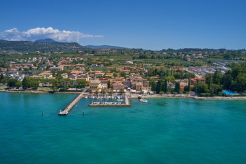 Obraz premium Aerial photography. Beautiful coastline. In the city of Bardolino, Lake Garda is the north of Italy. View by Drone. Docked yachts parking in Port.