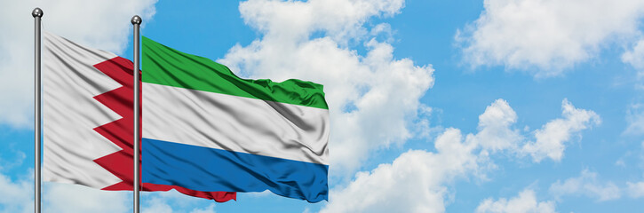 Bahrain and Sierra Leone flag waving in the wind against white cloudy blue sky together. Diplomacy concept, international relations.