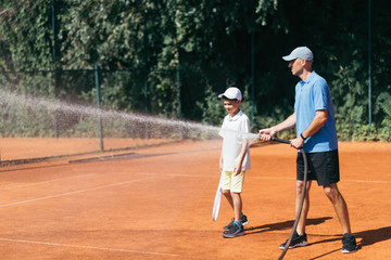 Tennis Coach Spraying a Clay Court with Water