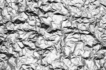 Flat lay closeup a sheet of silver gray wrinkled crumpled shiny glossy foil. Beautiful abstract modern trendy texture background