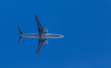 medium size blue passenger airplane on clear sky background. bottom view a few seconds before landing. composition photography. flying overhead to destination airport. travel and journey concept.