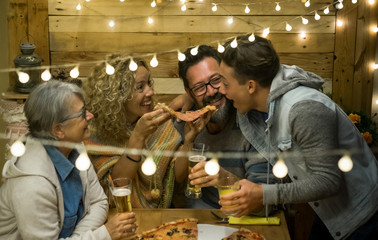 Multi generation family share together a big pizza. Parents with teenager son and grandmother. Wooden table and background. Concept of happiness and love.