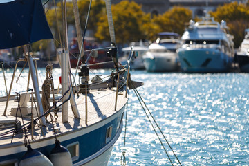 Board sailing yacht parked in the port on the background of other yachts, depth of field blur