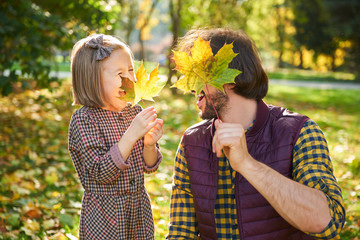 Obraz premium Father and his little daughter picking autumn leafs