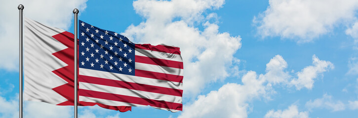 Fototapeta premium Bahrain and United States flag waving in the wind against white cloudy blue sky together. Diplomacy concept, international relations.