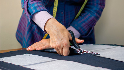 Detail of hands of dressmaker cutting a cloth to make a garment