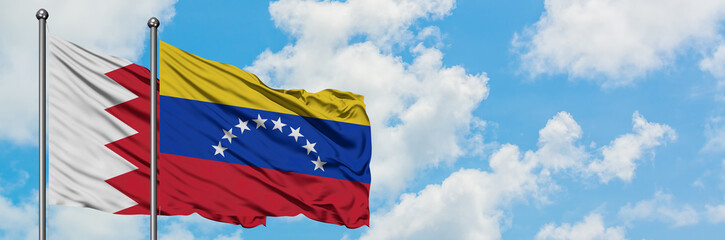 Naklejka premium Bahrain and Venezuela flag waving in the wind against white cloudy blue sky together. Diplomacy concept, international relations.