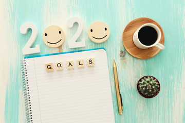 Business concept of top view 2020 goals list with notebook, cup of coffee over pastel blue wooden...