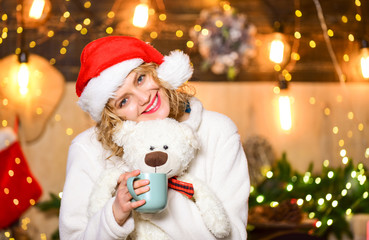 Fototapeta na wymiar Things to do before christmas. Woman with teddy bear drink tea christmas decorations background. Relax and recharge. Plan for some interesting Christmas activity. Girl with mug hot beverage relaxing