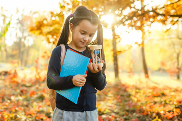 little girl holds hourglass in autumn