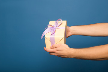 cropped view of man holding gift box isolated on blue
