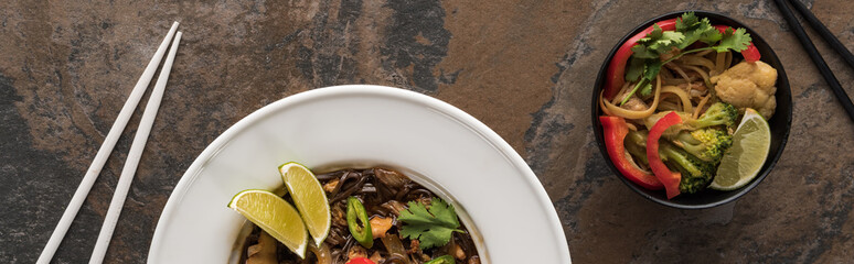 top view of thai noodles with beef and vegetables near chopsticks on stone surface, panoramic shot