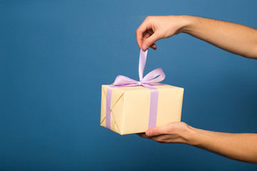 cropped view of man unpacking gift box isolated on blue
