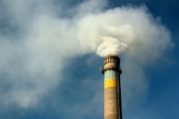 Smoking pipe of thermal power plant with Ukrainian flag colors against blue sky near Kharkiv, Eastern Ukraine