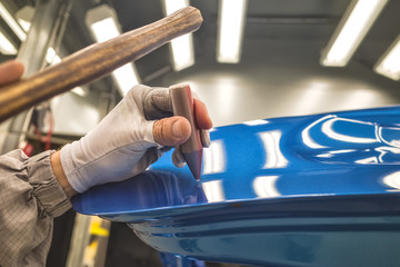 Employee car body painting shop eliminates a small metal defect