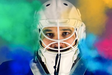 Detail of a male face in a white goalie hockey mask and  colored smoke.This is a detail hockey goalie. He is concentrated on game. He has  colored smoke around his face.