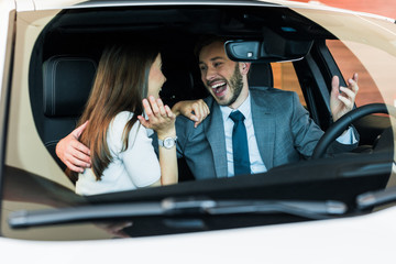 selective focus of excited bearded man looking at woman and gesturing in car