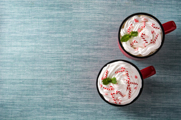 Peppermint coffee mocha decorated with candy canes for Christmas on blue background. Top view.  Copy space