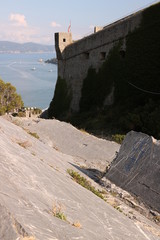 Fototapeta na wymiar Walls of the castle of Portovenere with turret and the background of the sea.