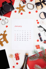 january calendar page, digital camera, champagne bottle, digital tablet, cosmetics, glasses, fir branch, earrings, red paper isolated on white